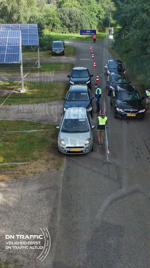 Dronebeeld van wachtende auto's bij de parkeeringang van het TT Circuit Assen, met servicemedewerkers van DN Traffic in geel hesje ernaast.